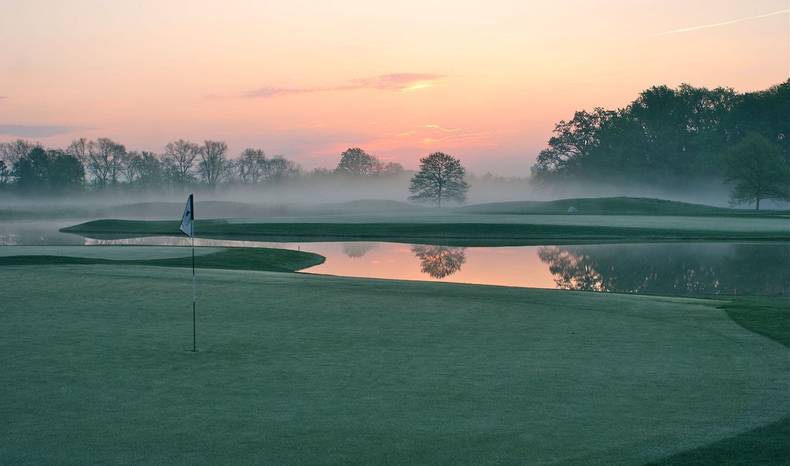 Golf course with a pond at sunrise